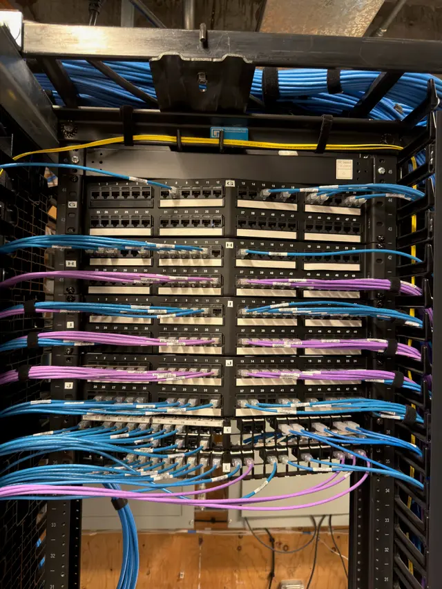 Rear of rack with color-coded patch cables organized by service