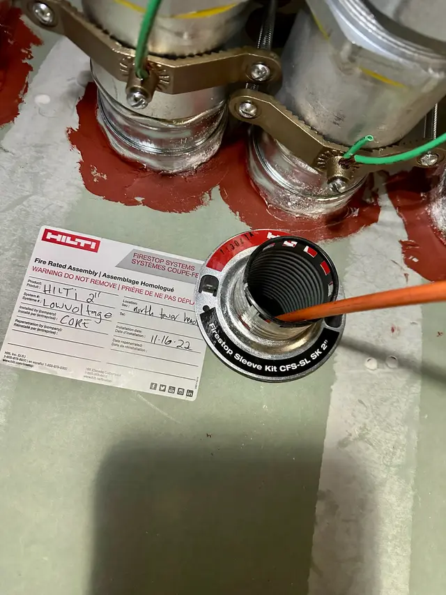 Hilti fire-rated firestop assembly documented and labeled at a low-voltage penetration