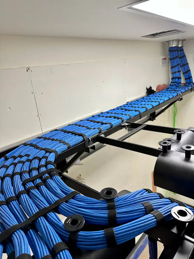 Blue Cat6 cable bundles combed and strapped along ladder rack