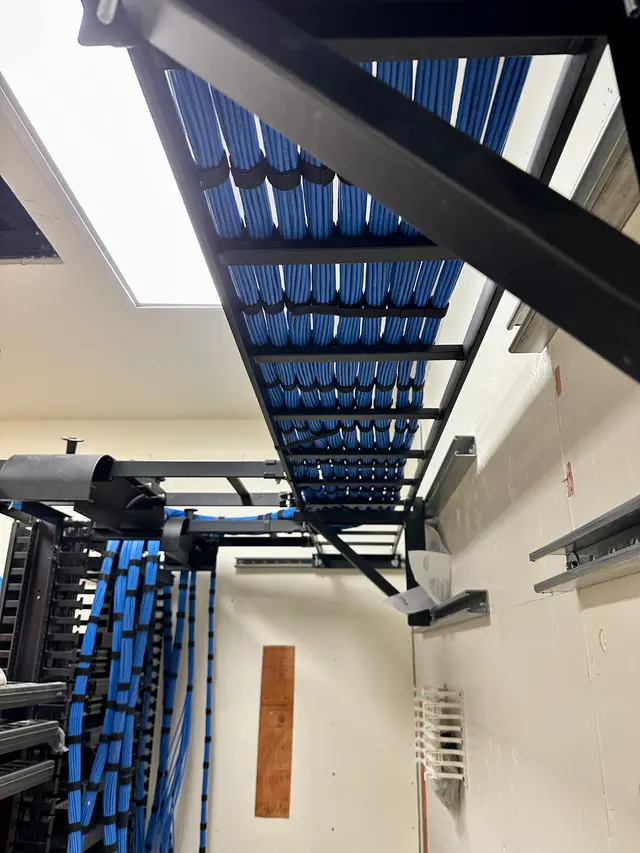 Overhead ladder rack dropping dressed Cat6 bundles into a hospital IDF rack
