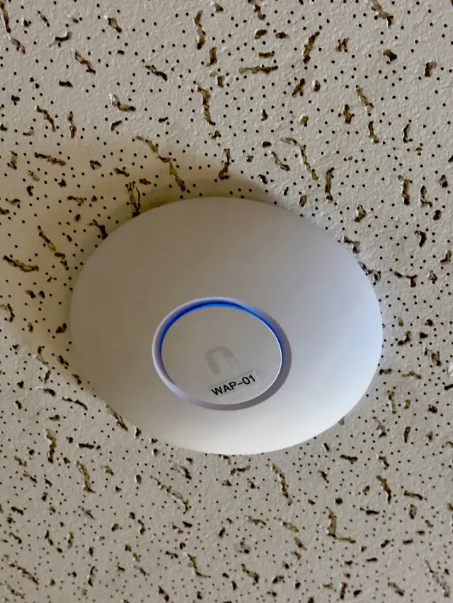 Ubiquiti wireless access point installed on a ceiling tile