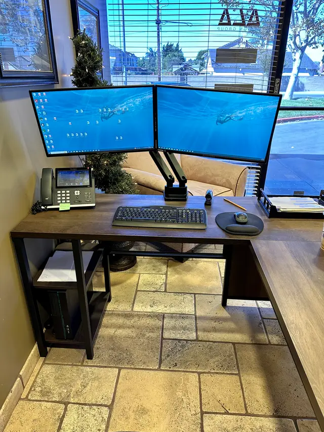 Desk setup with VoIP phone and dual monitors on an articulating arm